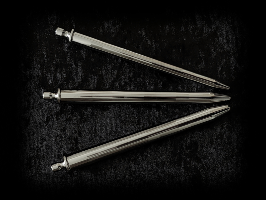 Three highly polished urethral dilators laying next to each other on black fabric background. The final Gentle stretcher production form.